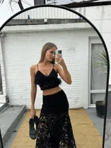 Top de encaje negro con escote en V, tirantes finos, detalles de terciopelo y plumas desmontables en el bajo.