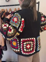 Saco negro de tejido de punto con mangas abullonadas y apliques de cuadrados de crochet multicolores.