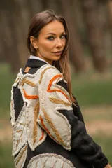 Cárdigan negro de lana con apliques de hojas en tonos beige, naranja y marrón.