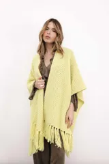 Ruana tejida en lana merino color amarillo pastel, con terminación de flecos.