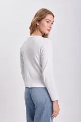 Remera blanca de algodón con textura acanalada, corte ajustado y mangas largas.
