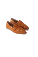 Mocasín de gamuza color terracota con detalle de tachas metálicas.