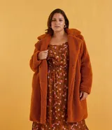 Campera larga color marrón óxido, de tejido sherpa con cuello solapa, cierre con botones y bolsillos laterales.
