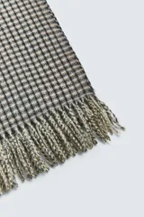 Bufanda rectangular con estampado de cuadros en tonos beige y negro, con flecos en los extremos.
