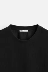 Camiseta negra de corte holgado, con cuello redondo y mangas cortas.