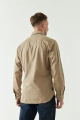 Camisa de gabardina gris con corte slim, mangas largas, cartera abotonada y dos bolsillos con solapa en el pecho.