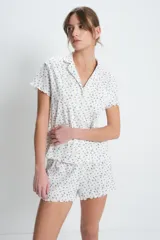Conjunto de pijama corto de algodón blanco con estampado de pequeñas flores azules. Incluye camisa de manga corta con cuello y botones, y short con cintura elástica y volados en el ruedo.