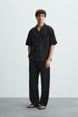 Pantalón negro de corte recto y calce relajado, confeccionado en tejido de algodón con elasticidad. Presenta cintura ajustable con cordón, bolsillos frontales y bolsillos traseros de doble vivo.