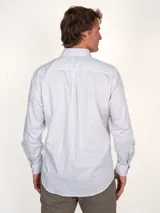Camisa de vestir de hombre, corte clásico, con estampado a cuadros en tonos rosa y celeste. Tiene cuello abotonado, bolsillo en el pecho y mangas largas.