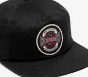 Gorro negro de algodón con visera plana y parche circular con el logo de Independent en el frente.