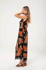 Vestido midi negro con estampado de flores naranjas y beige, espalda descubierta con tres botones en forma de flor, tajo lateral y flecos en el ruedo.