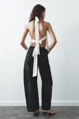 Top negro de satén con cuello halter drapeado ajustable con lazada en el cuello y espalda descubierta con lazada.
