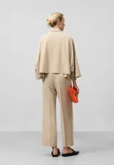Pantalón tobillero color beige, de corte recto, con trabillas, bolsillos laterales y bolsillos de vivo en la espalda.