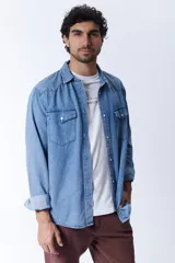 Camisa de manga larga de jean azul claro, con dos bolsillos con solapa abotonada en el pecho.