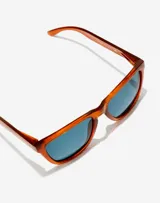 Lentes de sol Hawkers unisex con montura cuadrada color caramelo y lentes polarizadas azules.