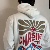 Canguro blanco con capucha y cordones ajustables, puños y cintura acanalados. Estampado en la espalda con un sol, olas y la frase "Chasing the waves Santa Barbara".