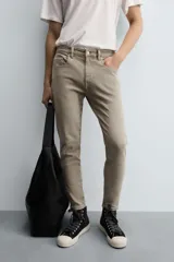 Pantalón de jean color beige, corte skinny, tiro medio, largo cropped y cinco bolsillos.