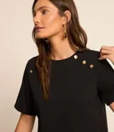 Blusa negra de crepé con cuello redondo, mangas cortas y botones decorativos dorados en los hombros.