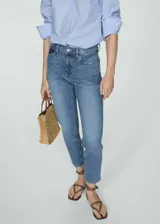 Pantalón de jean celeste, de corte mom-fit, tiro alto, con cinco bolsillos y cierre de cremallera y botón.