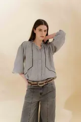 Blusa color beige con cuello mao con volantes, manga larga con puño elástico y cierre frontal con botones ocultos.