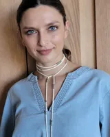 Collar marrón de cuero con cuentas doradas, con tiras finas que se atan al cuello y caen sobre el pecho.