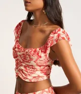 Blusa corta de tule con estampado de caracolas y peces en tonos rojo y blanco. Tiene escote cuadrado, mangas cortas con volados y fruncido en el busto.