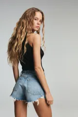 Short de jean de tiro alto, color celeste claro desgastado, con roturas grandes y deshilachado en el bajo. Presenta cinco bolsillos y cierre frontal con botón metálico.