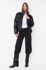 Campera puffer negra de cuero sintético, con cuello alto, cierre frontal con cremallera y bolsillos laterales.