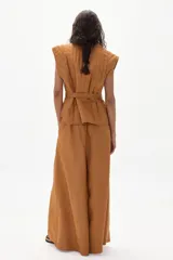 Pantalón de lino color marrón, de corte ancho con tiro medio-alto, tablas delanteras y elástico en la parte trasera.