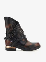 Bota corta de cuero bovino con efecto desgastado en tonos marrón y negro. Presenta un diseño de estilo rebelde con tachas metálicas en el caño, correas ajustables con hebillas y un detalle metálico dorado en el talón.