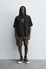 Camiseta negra de corte relaxed fit, cuello redondo y manga corta. Estampado frontal con dibujo de gato y texto en japonés.