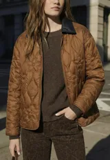 Campera capitoneada de color marrón con diseño de flores pespunteadas, cuello camisero en contraste oscuro y cierre frontal de cremallera.