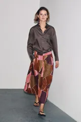 Falda midi de tiro alto confeccionada en hilatura de algodón con estampado geométrico multicolor. Detalle de pliegues en cintura y bajo evasé. Cierre con cremallera oculta en costura.