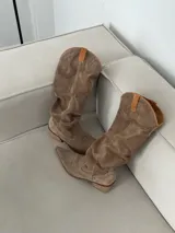Bota texana de cuero color marrón claro, con caña alta arrugada y detalles bordados en el empeine.