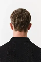 Remera polo negra de manga corta en punto trenzado con cuello clásico, tapeta de botones y bajo recto.