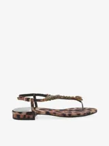 Sandalia con tira en el dedo y diseño con apliques dorados. Cuenta con pulsera ajustable en el talón y una base plana.