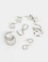 Set de seis pares de aros de metal plateado con cierre de tope a presión. Incluye aros tipo argolla de diferentes tamaños, grosores y texturas.
