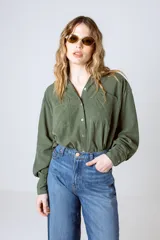 Camisa verde militar de manga larga con cuello camisero, cierre frontal con botones, dos bolsillos con solapa en el pecho y puños abotonados.