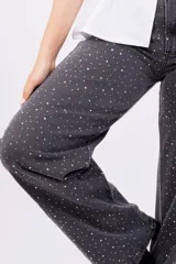 Pantalón de jean negro de corte wide leg con estampa de pequeñas estrellas blancas.