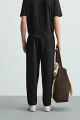 Pantalón verde militar de corte carrot fit, confeccionado en tejido de algodón. Cuenta con cintura elástica ajustable con cordón, bolsillos frontales y un bolsillo trasero de plastrón.