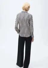 Camisa de manga larga con estampado de rayas verticales en blanco y negro, cuello camisero y cierre frontal oculto con botones.