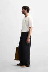 Camiseta blanca de corte holgado, cuello redondo y mangas cortas. Presenta un bordado y estampado combinado en el frente.