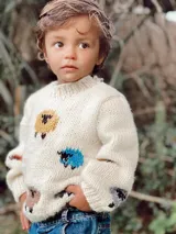 Sweater de lana color crema con cuello redondo y diseño de ovejas de colores bordadas a mano.