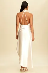 Vestido midi de satén color crema, con cuello halter y falda cruzada con abertura lateral y lazo en la cintura.