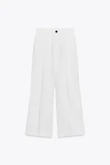 Pantalón blanco de corte ancho con pliegues frontales, tiro alto, cintura con trabillas, bolsillos laterales y de vivo en espalda. Cierre frontal con cremallera y botón.