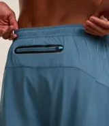 Bermuda deportiva azul con short de compresión interno, cintura elástica con cordón ajustable y bolsillo trasero con cierre.