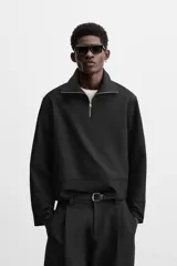 Sudadera negra de corte relaxed fit, con cuello alto y cierre frontal de cremallera metálica.