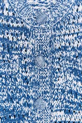 Chaqueta de punto azul y blanco con cuello redondo y manga francesa. Tiene bolsillos delanteros de plastrón y cierre frontal con botones a tono.