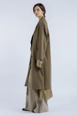 Tapado largo color verde oliva, de corte recto y silueta amplia, con diseño cruzado y cierre frontal de doble botonadura. Presenta solapas clásicas, hombros estructurados y largo por debajo de la rodilla. Confeccionado en lana y algodón.