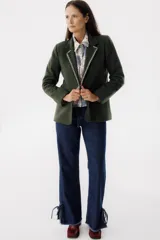 Blazer color camel de lana con solapas y cierre con botones. Presenta detalle de pespuntes blancos en los bordes.